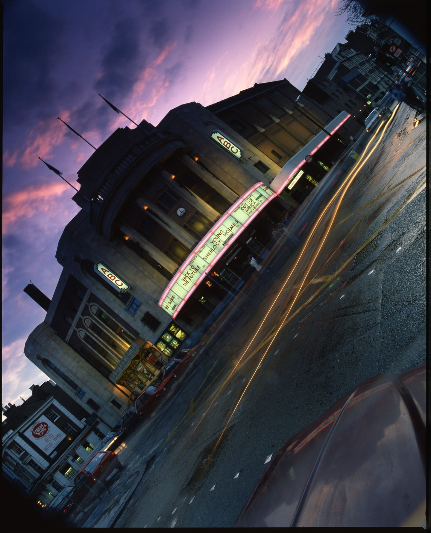 An angled view of the ABC cinema and traffic light trails beneath a purple evening sky.