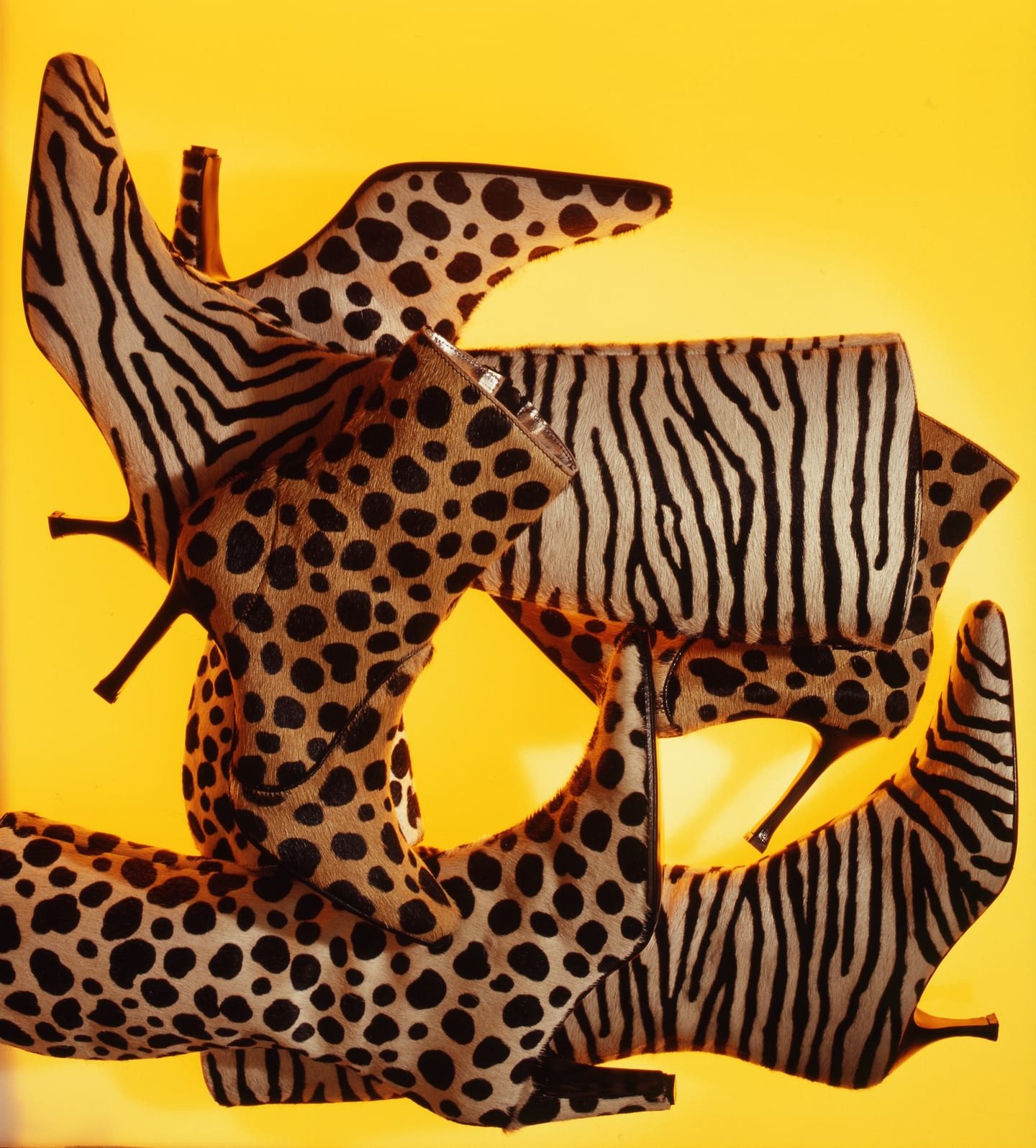 Heeled boots with spotted and striped patterns arranged against bright yellow.