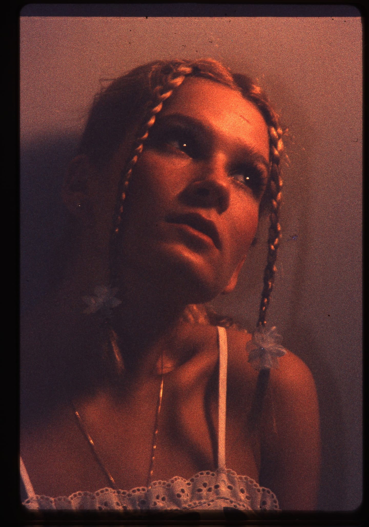 A woman with braided hair photographed in warm reddish light.