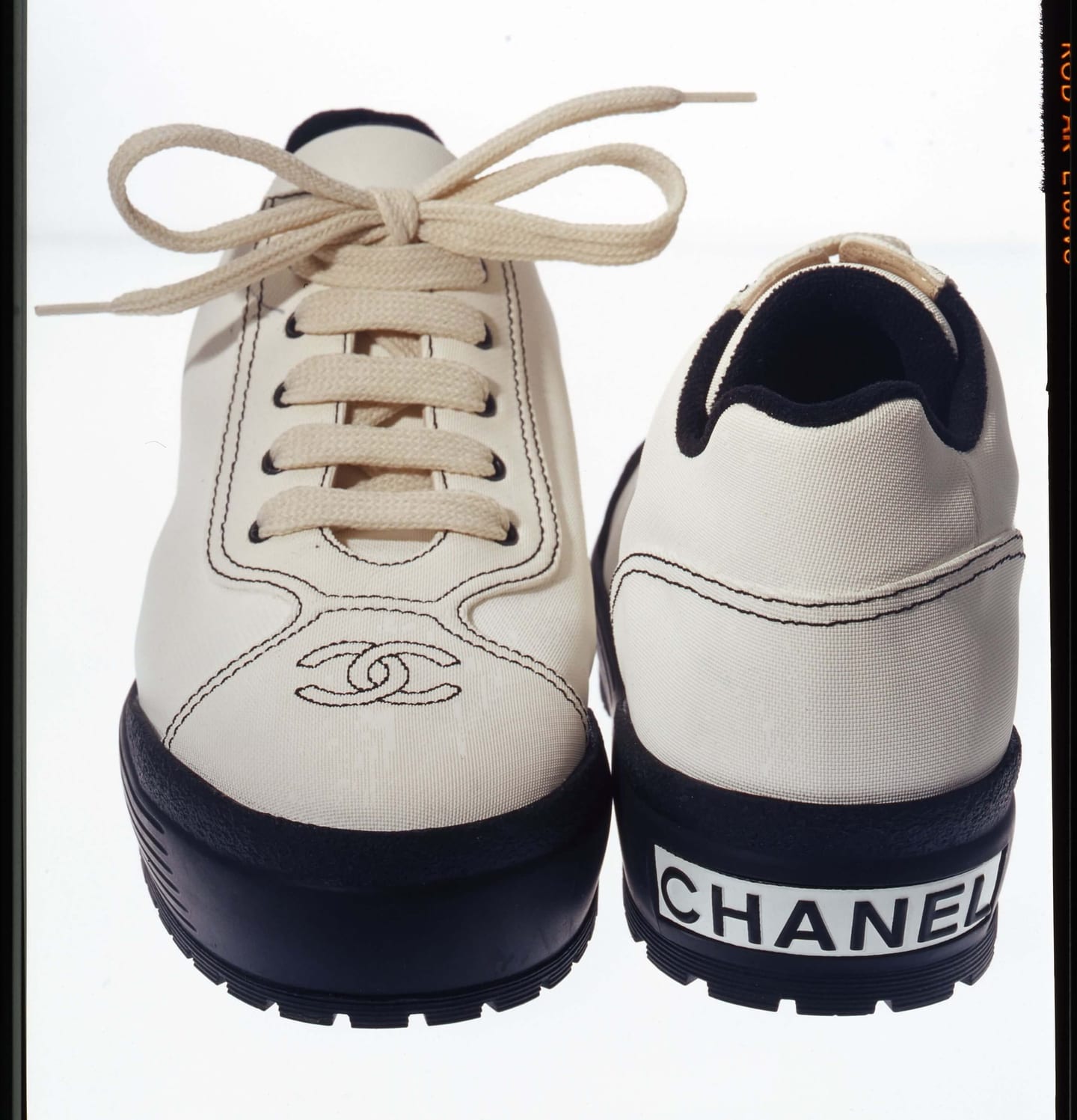 Two cream lace-up shoes seen from the front and back, with dark soles and Chanel lettering.